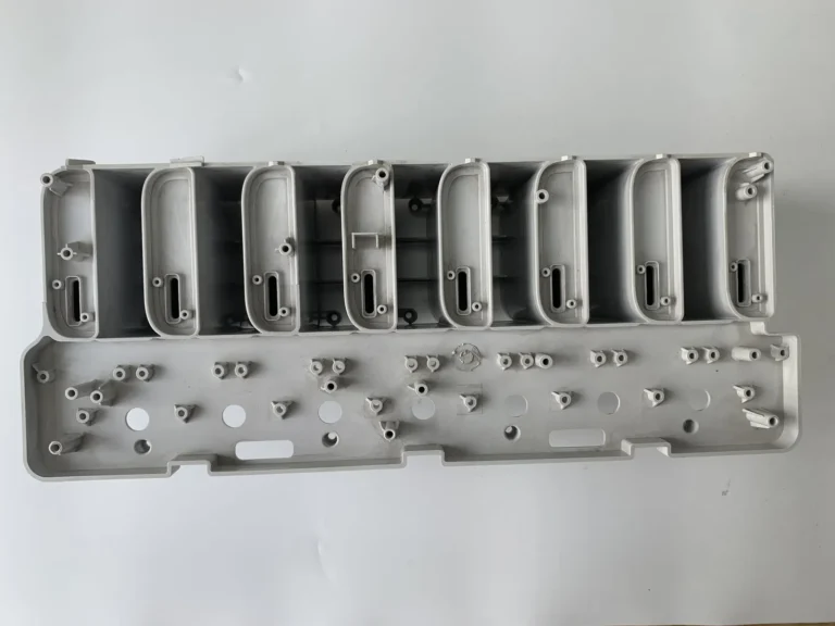 Eight-cavity family strip of grey moulded parts laid out for dimensional sampling